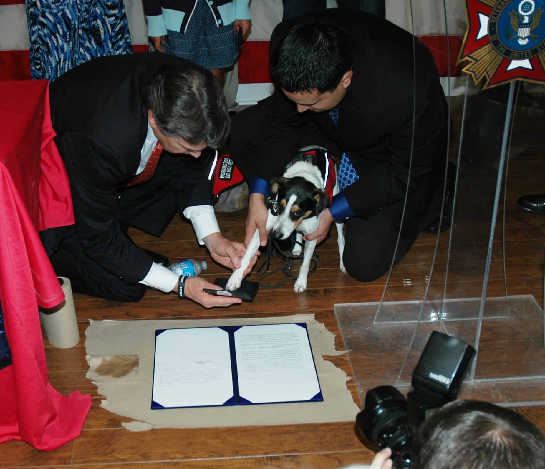 former Texas governor Rick Perry helping Bootz the dog put paw print on new law