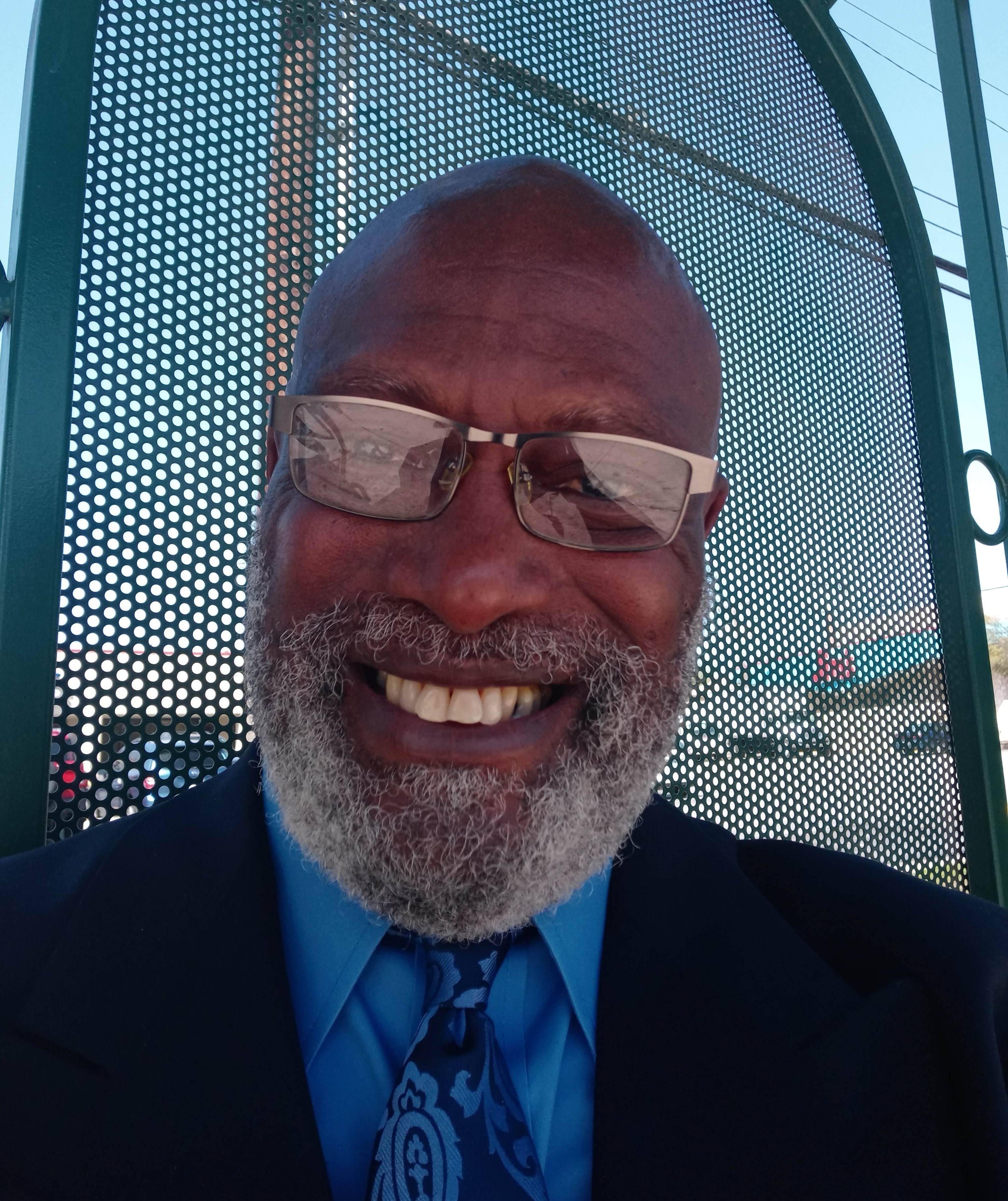 African American man with a beard and glasses smiling.