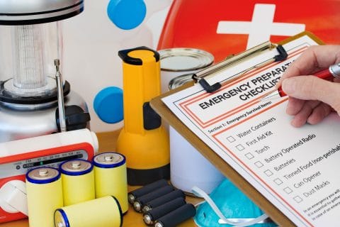 A person using an emergency checklist to see what supplies they have.