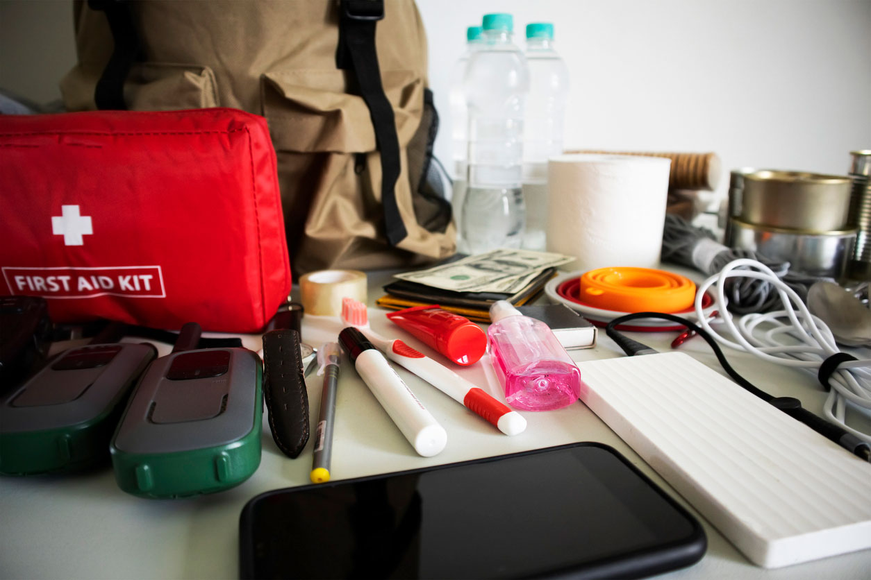 Emergency backpack equipment organized on the table. Documents, water, food, first aid kit and another items needed to survive.