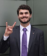 Gunnison Hays smiling and making the hook em sign with his hand.